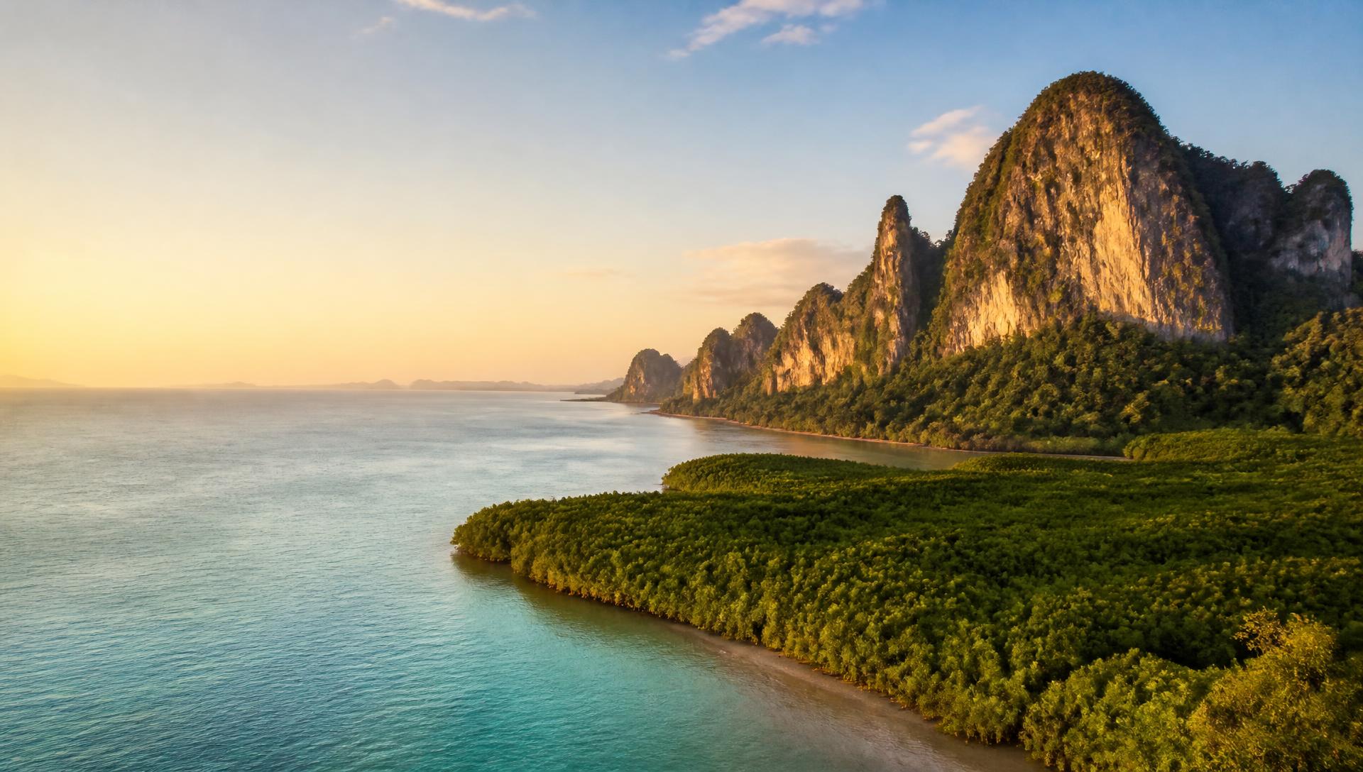 Andaman coastline in Phuket province — mangrove shoreline, limestone headland and turquoise sea at golden hour